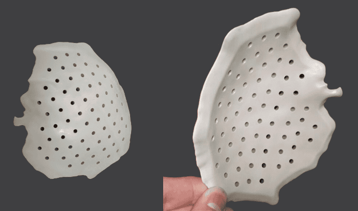 A lightweight, perforated ceramic or plastic component with a curved shape.