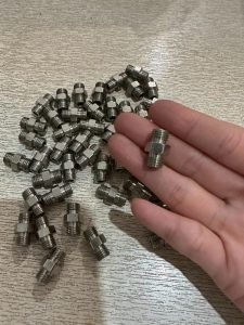High-precision CNC machined fittings for industrial applications, displayed on a wooden surface.