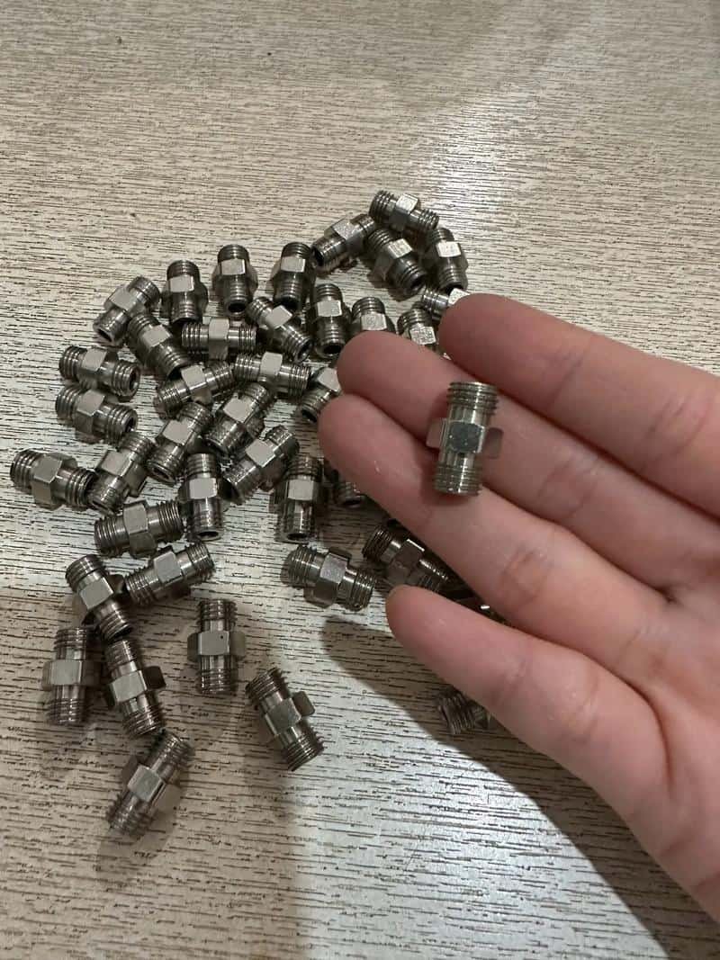 High-precision CNC machined fittings for industrial applications, displayed on a wooden surface.