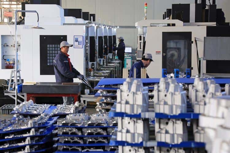 At 6CNC factory with operators working on CNC machine equipment.