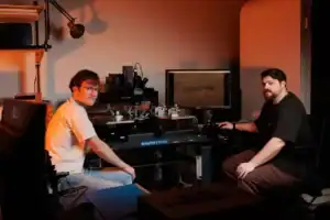 A technician and engineer working on CNC machinery in a workshop setting.