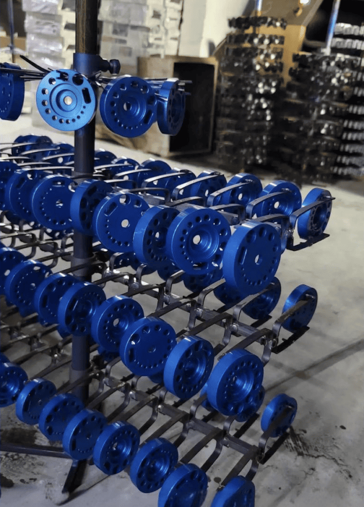 Blue CNC machined parts displayed on a rack in a manufacturing facility.
