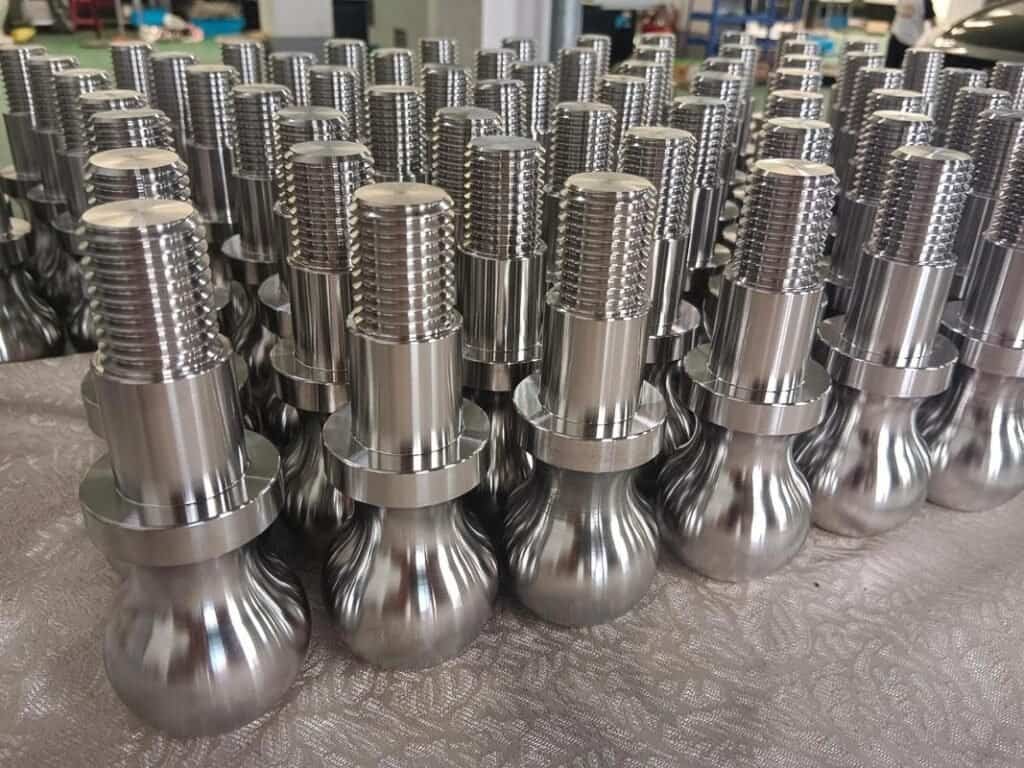 Precision machined metal components with threaded tops arranged in rows.